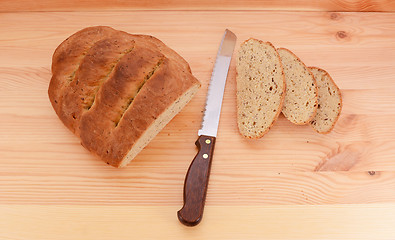 Image showing Fresh loaf of bread with a knife and three slices