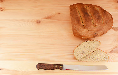 Image showing Fresh loaf of bread, cut slices and bread knife