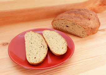 Image showing Two slices of bread on a red plate, with a loaf of bread