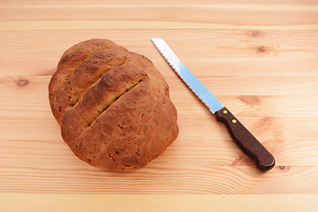 Image showing Freshly baked loaf with a bread knife 