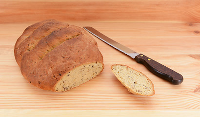 Image showing Freshly baked loaf of bread and bread knife on the table