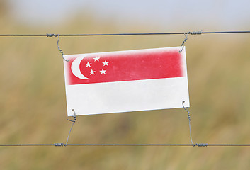 Image showing Border fence - Old plastic sign with a flag