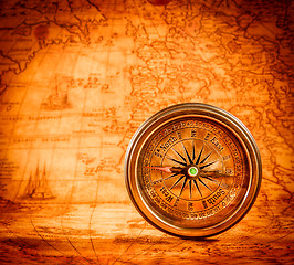 Image showing Vintage compass lies on an ancient world map.