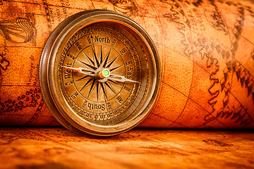 Image showing Vintage compass lies on an ancient world map.