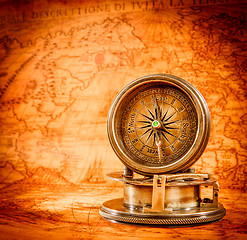 Image showing Vintage compass lies on an ancient world map.