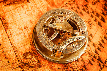 Image showing Vintage compass lies on an ancient world map.