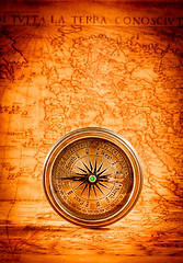 Image showing Vintage compass lies on an ancient world map.