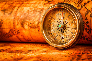 Image showing Vintage compass lies on an ancient world map.