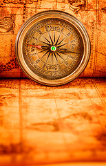 Image showing Vintage compass lies on an ancient world map.