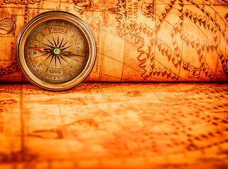 Image showing Vintage compass lies on an ancient world map.