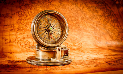 Image showing Vintage compass lies on an ancient world map.