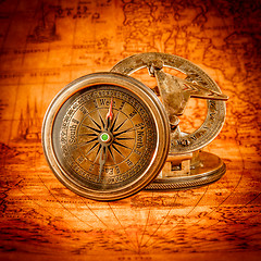 Image showing Vintage compass lies on an ancient world map.