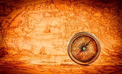 Image showing Vintage compass lies on an ancient world map.