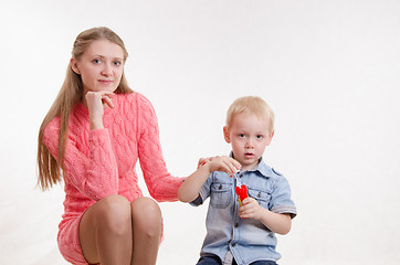 Image showing Serious boy blow bubbles with her mother