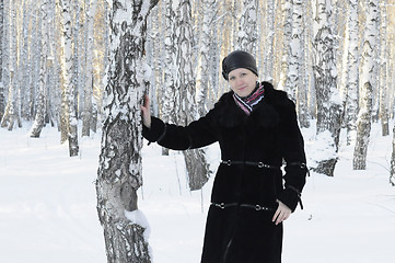 Image showing The woman in a black fur coat costs in the birch wood in the win