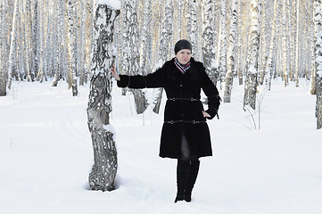 Image showing The woman in a black fur coat costs in the birch wood in the win