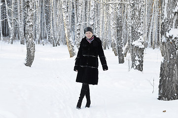 Image showing The woman in a black fur coat costs in the birch wood in the win