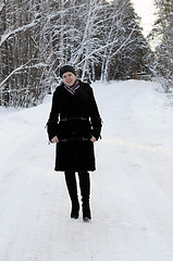 Image showing The woman in a black fur coat costs in the birch wood in the win