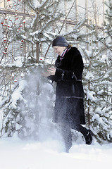 Image showing The cheerful woman in a black fur coat costs at snow-covered pin