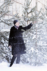 Image showing The cheerful woman in a black fur coat costs at snow-covered pin