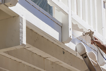 Image showing House Painter Spray Painting A Deck of A Home