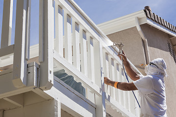 Image showing House Painter Spray Painting A Deck of A Home