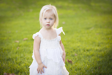 Image showing Adorable Little Girl Wearing White Dress In A Grass Field