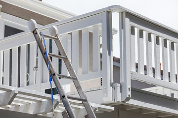 Image showing Construction Ladder and Painting Hose Leaning on House Deck