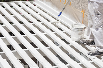 Image showing Painter Rolling White Paint Onto Top of Patio Cover