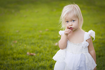Image showing Adorable Little Girl Wearing White Dress In A Grass Field