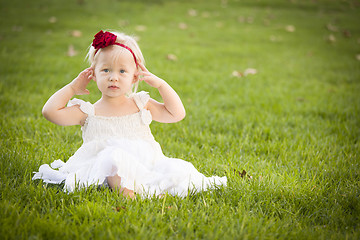 Image showing Adorable Little Girl Wearing White Dress In A Grass Field