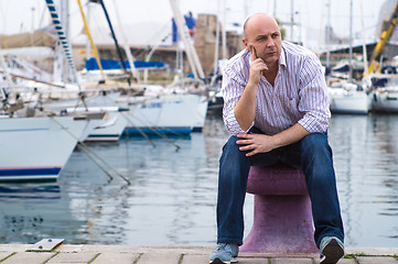 Image showing Businessman sitting by expensive sailing boats and yachts in a c