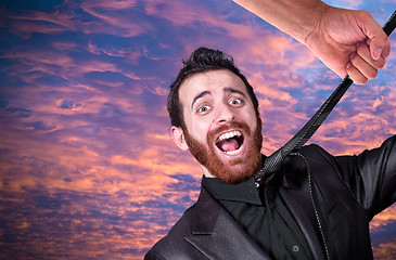 Image showing Big hand grabbing the necktie of young businessman