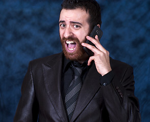 Image showing Man in business suit shouting into his mobile phone