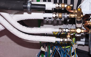 Image showing white pipes brass nozzles valves and multicolored wires in indus