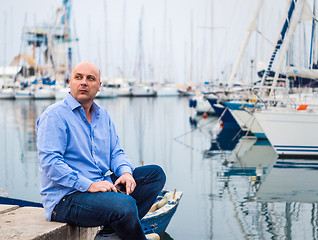 Image showing Businessman sitting by expensive sailing boats and yachts in a c