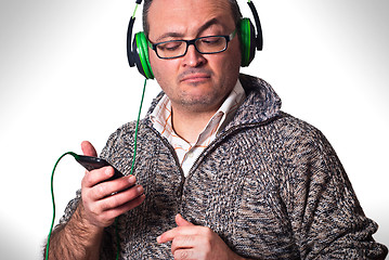 Image showing man listening to music and looking at cell phone with puzzled lo