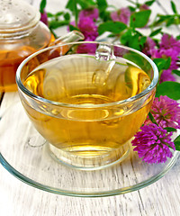 Image showing Tea with clover in glass cup on light board