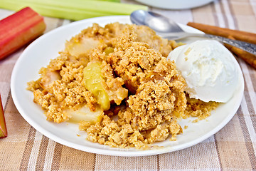 Image showing Crumble with rhubarb and ice cream in bowl on linen tablecloth