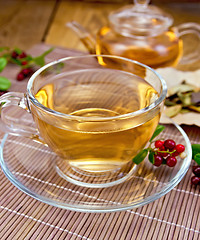 Image showing Tea with lingonberry in glass cup on bamboo napkin