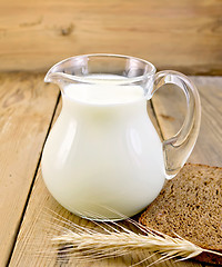 Image showing Milk in glass jug with bread on board