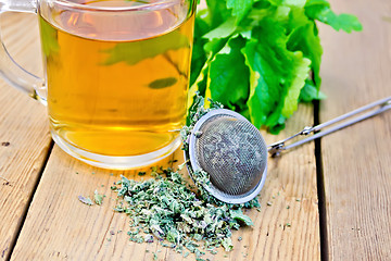 Image showing Herbal tea with mint in mug with strainer on board