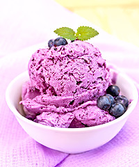 Image showing Ice cream blueberry with mint in bowl on purple napkin