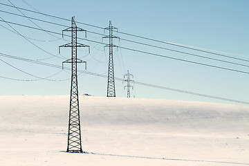 Image showing High voltage electricity power pylon on snowy field