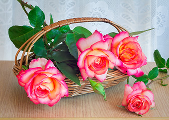 Image showing Beautiful large roses with leaves in a wicker basket on the tabl