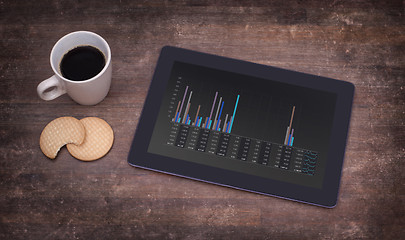 Image showing Tablet touch computer gadget on wooden table, graph