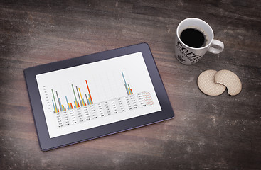 Image showing Tablet touch computer gadget on wooden table, graph