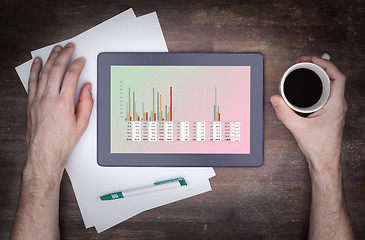 Image showing Tablet touch computer gadget on wooden table, graph