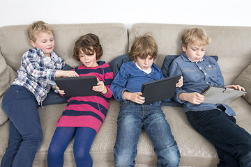 Image showing Brothers And Sister Using Digital Tablets On Sofa