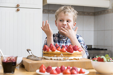 Image showing Boy Licking Finger with Strawberry Cake batter behind a kitchen 